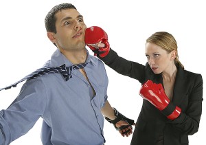 punch Corporate woman with boxing gloves striking a man in a tie