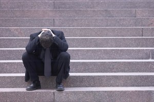 Upset man on stairs with his head in his hands