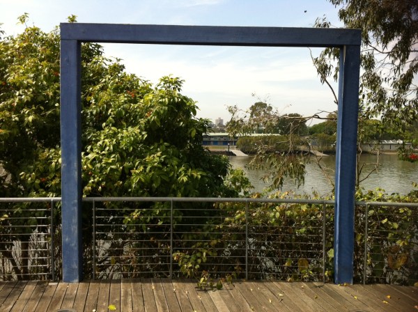 A wooden frame by the river, view obscured by trees.