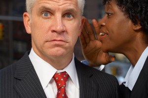 Woman whispering in a man's ear.