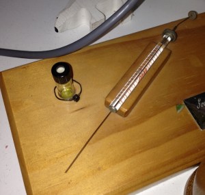 A syringe and needle mounted on a board
