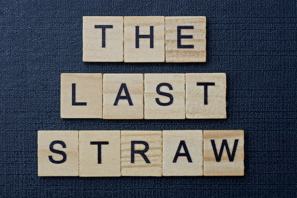 phrase the last straw in small square wooden letters on a black background